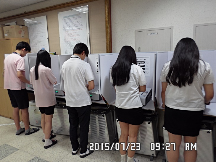 운암고 학생들이 터치스크린 투표기를 통해 자신이 원하는 학생회 임원에 투표를 하고 있는 모습의 사진입니다.