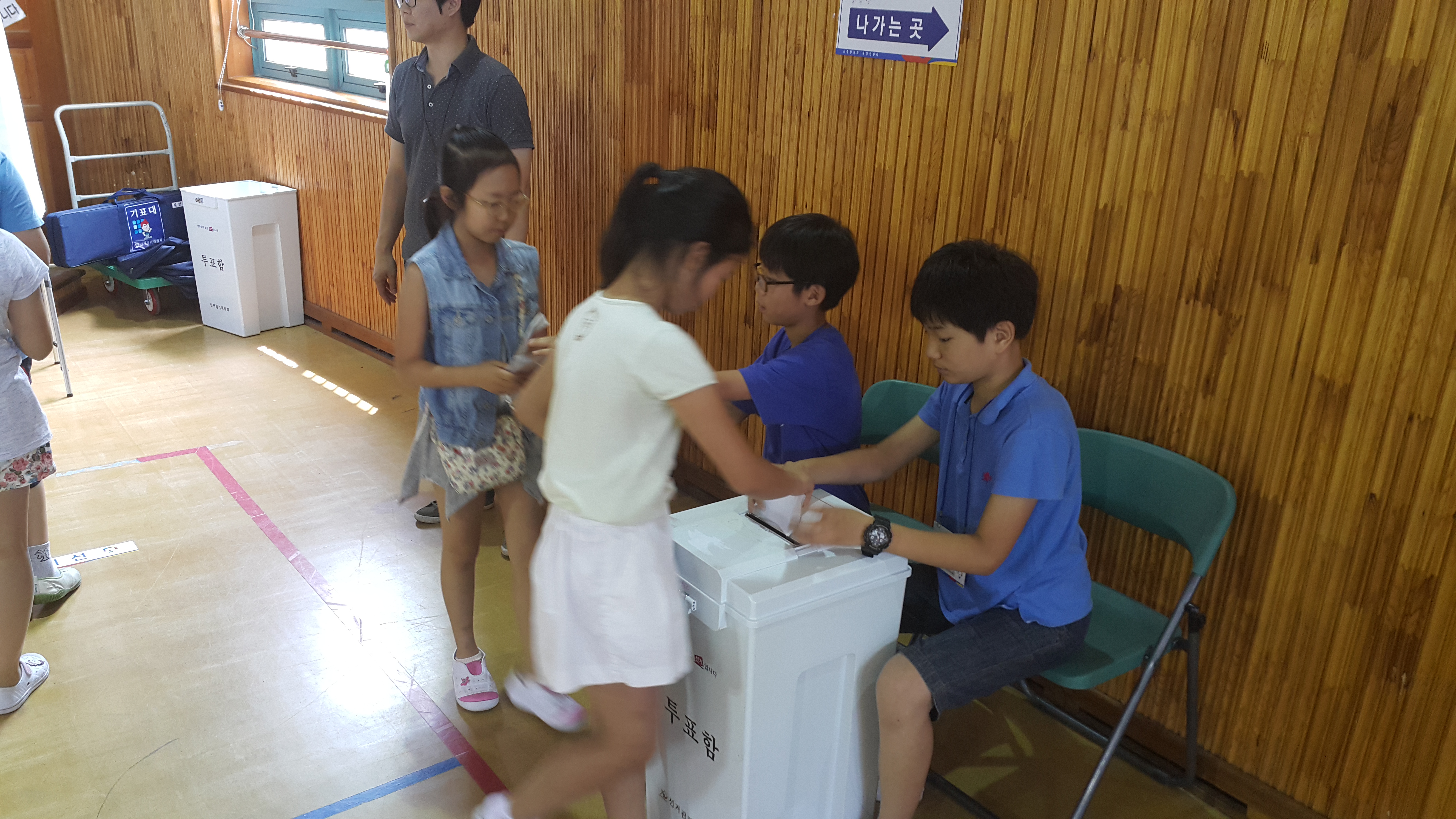 투표를 마친 학생들이 투표지를 투표함에 투입하고 있는 모습의 사진입니다.