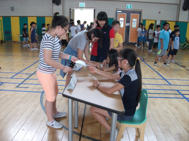 송전초등학교 학생들이 본인확인석에서 본인확인 후 투표용지를 수령하고 있는 모습의 사진입니다.