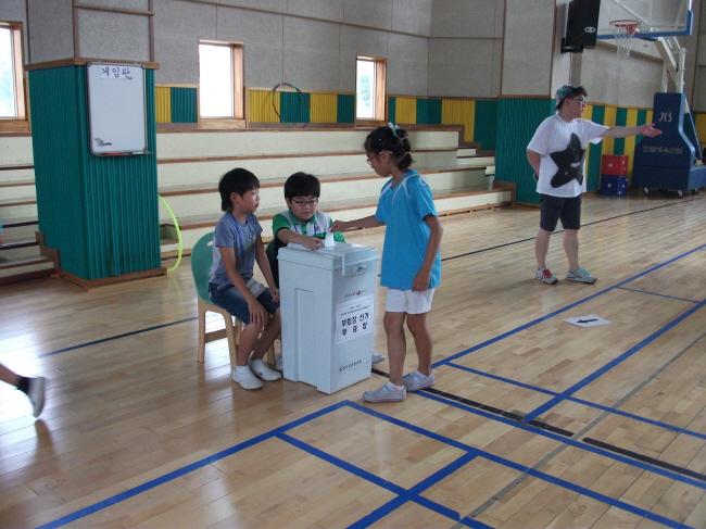 투표를 마친 학생들이 투표지를 투표함에 투입하고 있는 모습의 사진입니다.