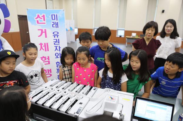 선거체험에 참여한 어린학생들이 투표지분류기를 이용하여 