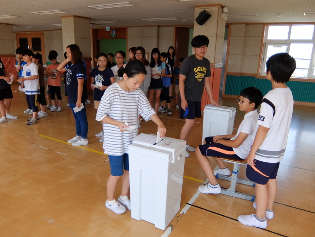 학생들이 기표소에서 투표한 투표용지를 투표함에 투입하는 사진