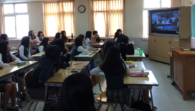 학생들이 교실에 설치된 TV를 통하여 홍보영상을 시청하는 모습  