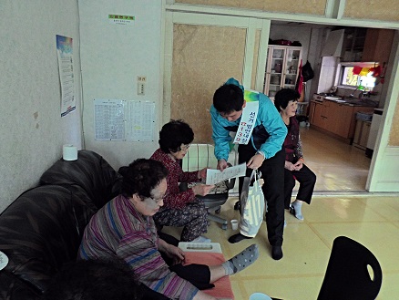 오산시선거관리위원회에서 관내 경로당을 방문하여 어르신들께 신고전화 1390에 대한 안내문을 나눠드리는 모습의 사진입니다
