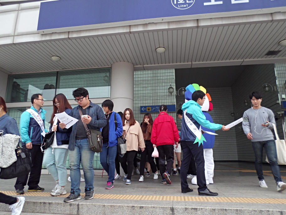 오산시선관위 직원들이 오산대역을 이용한 오산대 학생들에게 홍보용품을 나눠주며 투표참여를 당부하고 있는 모습의 사진입니다.