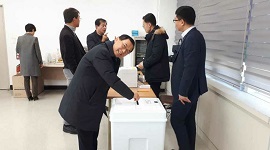 광주시위원회 3층 회의실에서 선거체험하는 사진(투표함에 투표용지를 투입하는 장면)